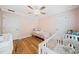 Bedroom with hardwood floors, light pink walls, and featuring a crib and changing table at 1904 Rosewood Ln, Woodstock, GA 30189