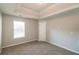 A cozy bedroom with tray ceiling, neutral paint, carpet flooring, and natural light from a window at 6251 Lamp Post Pl, Atlanta, GA 30349