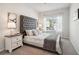 Cozy bedroom with tufted headboard, neutral decor, and bright natural light from the window at 11837 Rizvan Pl, Covington, GA 30014