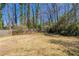 Large, grassy backyard with a wooden fence and mature trees in the background at 6050 Randy Ln, Ellenwood, GA 30294