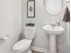 Elegant powder room features a white pedestal sink and toilet, complemented by stylish decor at 11102 Suria Dr, Covington, GA 30014