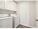Functional laundry area featuring modern washer and dryer units under convenient overhead cabinets at 11102 Suria Dr, Covington, GA 30014