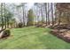 Spacious backyard featuring a well-maintained lawn, bordered by mature trees, perfect for outdoor activities at 3034 Farmington Se Dr, Atlanta, GA 30339