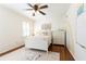 Cozy bedroom with a ceiling fan, string lights, charming decor, a large window with shutters, and hardwood floors at 3034 Farmington Se Dr, Atlanta, GA 30339