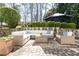 Lovely patio with ample seating under a large umbrella surrounded by lush greenery and natural stone walls at 3034 Farmington Se Dr, Atlanta, GA 30339