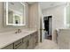 A bright bathroom featuring dual sinks, illuminated mirrors, and a doorway leading to the bedroom at 2125 Burnside Nw Dr, Atlanta, GA 30318