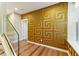 Hallway with hardwood floors, glass railing and unique gold patterned accent wall at 2125 Burnside Nw Dr, Atlanta, GA 30318