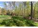 Lush green backyard featuring mature trees, garden beds, and an inviting outdoor space at 6165 Lake Oak Lndg, Cumming, GA 30040