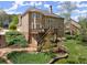 Exterior of a multi-story home with a deck, stairs, landscaped garden beds, and lush greenery at 6165 Lake Oak Lndg, Cumming, GA 30040