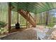 Covered patio featuring stone flooring, outdoor stairs and seating area overlooking serene wooded surroundings at 6165 Lake Oak Lndg, Cumming, GA 30040