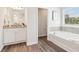 A view of the bathroom showcasing a soaking tub with tiled walls and wood-look flooring at 11841 Rizvan Pl, Covington, GA 30014