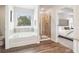 Well-lit bathroom featuring a separate shower and soaking tub, plus a view to the bedroom at 11841 Rizvan Pl, Covington, GA 30014