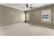 Spacious carpeted bedroom featuring a ceiling fan and two windows at 3405 Camellia Ln, Suwanee, GA 30024