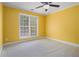 Bedroom with yellow walls, ceiling fan, and window overlooking the yard at 907 Hindman Pl, Mcdonough, GA 30253