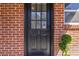 Close-up of a brick facade featuring a black front door with window panels and a topiary at 4282 Roswell Ne Rd # G1, Atlanta, GA 30342