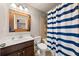 Well-lit bathroom showcasing a framed mirror, vanity, toilet, and a shower with a striped curtain at 4467 Sterling Pointe Nw Dr, Kennesaw, GA 30152