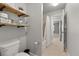 A bathroom showcasing a toilet, open shelving, and shower/tub combo with tile floor and light gray walls at 4467 Sterling Pointe Nw Dr, Kennesaw, GA 30152