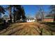 View of the backyard showcasing the home's exterior, lawn, and mature trees under a bright blue sky at 110 Raymond St, Jonesboro, GA 30236