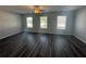 Spacious living room featuring gray wood floors, ceiling fan, and many windows at 8666 Webb Rd, Riverdale, GA 30274