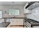 Updated kitchen with stainless steel appliances, gas range, marble backsplash, granite countertops, and white cabinets at 245 Davenham Ct, Alpharetta, GA 30005