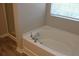 Bright white tub accented by wood-look flooring and window light at 83 Nyishol Way, Dallas, GA 30157