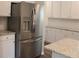 Stainless steel refrigerator and granite countertops, complete with white cabinets, in this bright kitchen at 83 Nyishol Way, Dallas, GA 30157