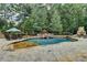 Beautiful backyard oasis with a swimming pool, waterfall feature, and a stone patio surrounded by trees at 829 Big Horn Holw, Suwanee, GA 30024
