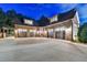 Elegant brick home showcasing a spacious driveway and four-car garage with custom wood doors under dormered windows at 829 Big Horn Holw, Suwanee, GA 30024