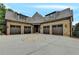 A large brick home with a circular driveway and multiple garages, creating an inviting curb appeal at 829 Big Horn Holw, Suwanee, GA 30024