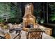 An outdoor stone fireplace on a brick patio with outdoor seating illuminated at nighttime at 829 Big Horn Holw, Suwanee, GA 30024
