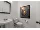 Stylish powder room with a pedestal sink, decorative mirror, and framed art, combining functionality and aesthetic appeal at 2009 Kensington Green Se Dr, Smyrna, GA 30080