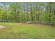 Fenced backyard featuring a large green lawn, mature trees, and a prebuilt dog house at 60 Cypress Dr, Covington, GA 30016