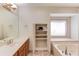 Bathroom with wooden cabinets, open shelving, soaking tub, and large mirror at 1667 Manhasset Farm Ct, Atlanta, GA 30338