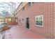 Brick home featuring a ground-level door, multiple windows, and brick patio in a wooded backyard at 407 North Ave, Atlanta, GA 30354