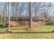 Quaint brick home with dark shutters, complemented by mature trees, nestled in a serene front yard setting at 407 North Ave, Atlanta, GA 30354