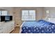 Bright bedroom featuring hardwood floors, a large window, a full-sized bed, and dresser with TV at 4087 Signal Rdg, Lilburn, GA 30047