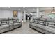 Open-concept living room boasts modern gray couches, wood floors, and a view into the updated kitchen area at 4087 Signal Rdg, Lilburn, GA 30047