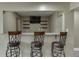 Basement bar area boasts granite countertops, a TV, shelves, and comfortable seating at 1698 Little Fox Ln, Dacula, GA 30019