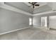 Large bedroom featuring a tray ceiling, neutral carpet, and access to a hallway at 1698 Little Fox Ln, Dacula, GA 30019
