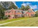 Charming brick home with a well-maintained lawn and symmetrical design, complemented by lush greenery and blue skies at 5581 Stapleton Dr, Dunwoody, GA 30338