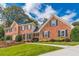 A stately brick residence with manicured lawns, showcases classic architectural details and charming green shutters at 5581 Stapleton Dr, Dunwoody, GA 30338