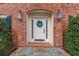 Inviting front door with a festive wreath, set in a brick surround with elegant sconces and a welcoming mat at 5581 Stapleton Dr, Dunwoody, GA 30338