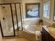 A bathroom featuring a soaking tub, a glass-enclosed shower, and travertine tile surround at 10390 Rivertown Rd, Fairburn, GA 30213