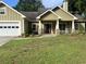 One-story home with an attached garage, a front porch with columns, and green siding at 10390 Rivertown Rd, Fairburn, GA 30213