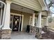 Inviting front porch with stone-based columns and a decorative glass front door at 10390 Rivertown Rd, Fairburn, GA 30213