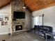 Inviting living room displaying a stone fireplace, dark sofa, wood-look floors, and vaulted ceiling at 10390 Rivertown Rd, Chattahoochee Hills, GA 30213