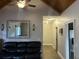 Comfortable living room showcasing a dark leather sofa, mirror, and wood-look floors under a vaulted ceiling at 10390 Rivertown Rd, Chattahoochee Hills, GA 30213