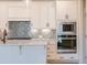 Kitchen with stainless steel built-in appliances, white cabinetry, and stylish backsplash at 108 Redford Ln, Canton, GA 30115