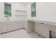 Well-lit laundry room with white cabinets, marble countertops, patterned floors, and backyard view at 1171 Lupo Loop, Chattahoochee Hills, GA 30268