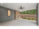 This covered patio features a stone fireplace, ceiling fan, and a view of the landscaped backyard at 1171 Lupo Loop, Chattahoochee Hills, GA 30268
